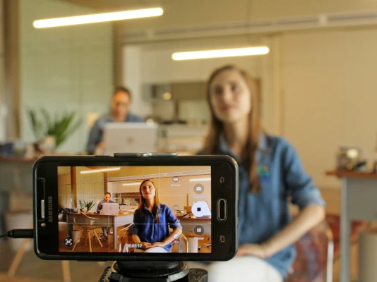 I tuoi video per il web sono uno strumento formidabile di promozione Lo schermo di un cellulare mentre riprende una ragazza in uno studio professionale. I tuoi video per il web sono uno strumento formidabile di promozione
