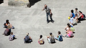 Uomo in piedi in mezzo a un semicerchio di ragazzi seduti che lo ascoltano. I nostri corsi sono la trasmissione del saper fare