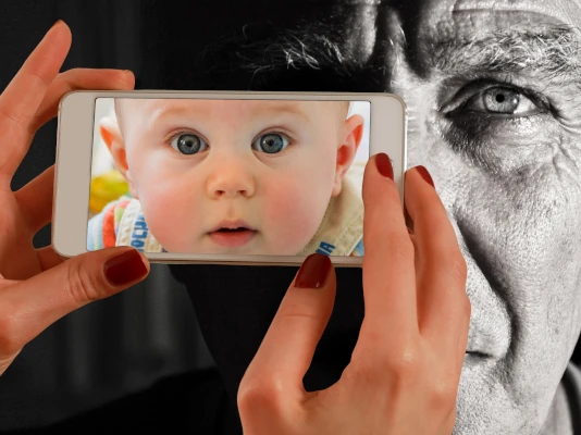 Mani di donna impugnano uno smartphone per fotografare un uomo anziano, ma nello schermo si vede invece un bambino. I clienti non capiscono che l'aspetto dei siti cambia secondo chi lo guarda